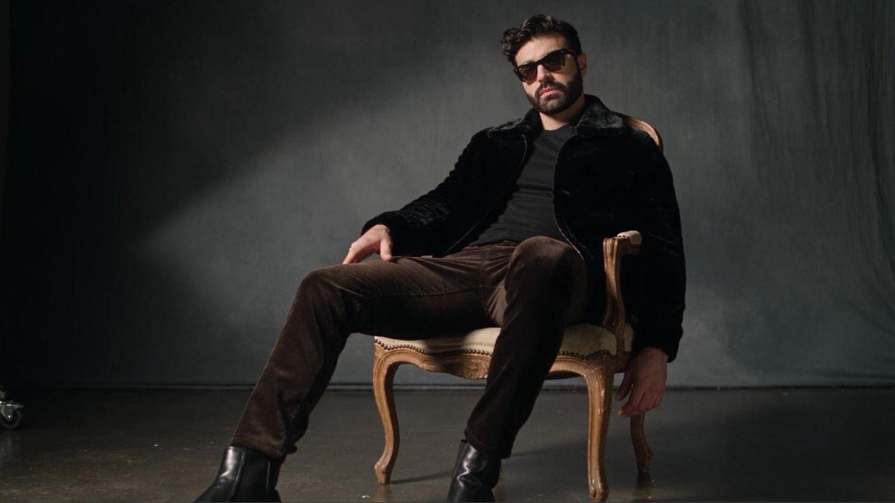 ADOM singer songwriter seated in a velvet jacket, from the Radar Online feature.